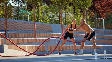 Açık havada formda vücut eğitimi almış azimli bir adam. Halat egzersizleri yapıyor. Şehir merkezinde, güç ve dayanıklılık gösteriyor. Spor anlayışı, aktif ve sağlıklı yaşam tarzı, fitness