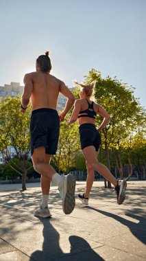 Genç adam ve kadın vücutlarını formda tutuyorlar, sabahın erken saatlerinde koşuyorlar, açık havada koşuyorlar, dayanıklılık ve dayanıklılık artıyorlar. Spor anlayışı, aktif ve sağlıklı yaşam tarzı, fitness