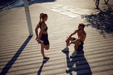 Siyah spor giysili genç bir kadın antrenman yapıyor. Koçla yoğun antrenman yapmadan önce ısınma hareketleri yapıyor. Spor anlayışı, aktif ve sağlıklı yaşam tarzı, fitness