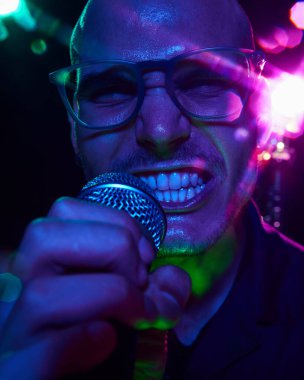 Neon ışıkları şarkıcıların yüzüne tutku vurgular, canlı performans sırasında sesinin yoğunluğunu ve gücünü yakalar. Müzik ve parti kavramı, hobi ve iş, enerji, müzik festivalleri. Ad