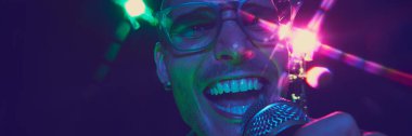 Pankart. Canlı müziğin gücü şarkıcıların yüzüne yansıyor. Dinamik neon ışıklarıyla vurgulanıyor ve kalbi mikrofona dökülüyor. Müzik ve parti kavramı, hobi ve iş, enerji, müzik festivalleri. Ad