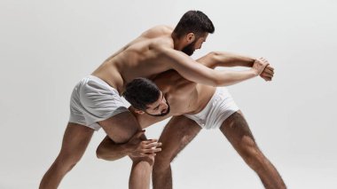 Kaslar gergin ve zihinler odaklanmış. İki güreşçi, hem fiziksel hem de zihinsel olarak gri arka plana karşı savaşıyor. Erkek sağlığı, güzellik ve moda, fitness, erkeklik kavramı. Ad.