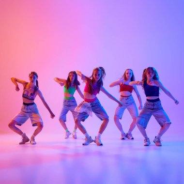 Tarz sahibi gençler senkronize bir şekilde dans ediyor ve müzik eşliğinde bireyselliklerini neon ışıklarıyla gradyan arka planda ifade ediyorlar. Spor ve hobi kavramı, çocukluk, hareket.