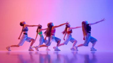 Bir grup yetenekli genç kız, neon ışıkta dans ederek, değişken pembe arka planda dans ediyorlar. Spor ve hobi kavramı, çocukluk, arkadaşlık, hareket. Dans okulu.