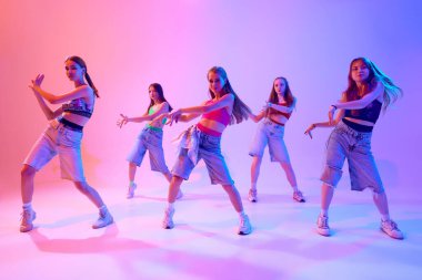 Gruplar birliği, her hareketin neon ışıkta gradyan pembe arka plana karşı hikaye anlattığı bu elektrik performansında parlıyor. Spor ve hobi kavramı, çocukluk, hareket. Dans okulu.