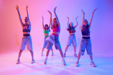 Akışkan hareketler ve güçlü ifadeler bu dansı neon ışıklarıyla gradyan pembe arkaplana karşı yapar. Gençler gösteri yapıyor. Spor ve hobi kavramı, çocukluk, arkadaşlık, hareket. Dans okulu.