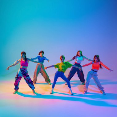 Dansçılar, kızlar duygusal ve güçlü bir performans sergiliyorlar. Neon ışıklarıyla gradyan stüdyonun arka planına karşı. Spor ve hobi kavramı, çocukluk, arkadaşlık, hareket. Dans dersleri..