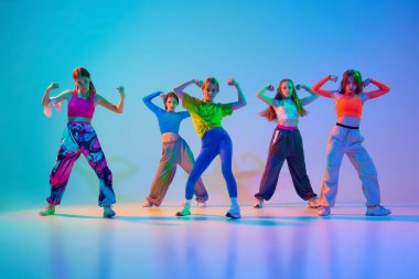 Sanat gösterisi. Yetenekli genç kızlar, duygu ve güç dolu, neon ışıkta dans eden hip hop, gradient stüdyo arka planına karşı. Spor ve hobi anlayışı, arkadaşlık, hareket. Dans dersleri..