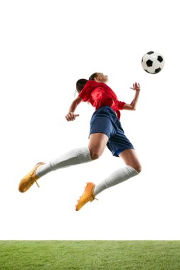 Uzun boylu bayan futbolcu göğsüyle ya da kafasıyla stadyumdaki izole beyaz arka planda topa atlıyor. Kadın ve spor kavramı, takım oyunları, hareket, zafer, aksiyon. Ad