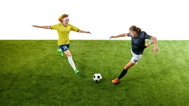 İki genç kadın, yoğun futbol oyuncuları, havadalar ve yeşil sahada hareket halindeler, her ikisi de top kontrolü için birbirlerini alt etmeye çalışıyorlar. Spor, yarışma, turnuva, oyun, etkinlik kavramı.
