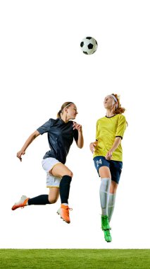 İki atletik kadın, 20 'li yaşlarda, futbol oyuncuları, havadaki topa odaklanmış, her ikisi de futbol sahasında kontrolü ele almak için pozisyon alıyorlar. Spor, yarışma, turnuva, oyun, etkinlik kavramı.