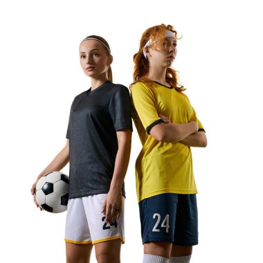 Genç atletik kadınlar, futbol oyuncuları, arka arkaya sahada duruyorlar, topu tutuyorlar, ikisi de güçlü ve kendinden emin duruyorlar. Spor, yarışma, turnuva, oyun, etkinlik kavramı.