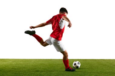 Kırmızı-beyazlı kararlı futbolcu, beyaz stüdyo arkaplanına karşı antrenman yaparken atlama vuruşu yapıyor. Dinamik fotoğraf. Şampiyonluk konsepti, spor müsabakaları, final maçı. Ad
