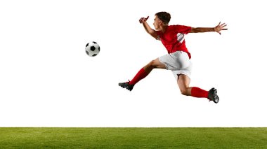 Kırmızı ve beyazlı genç futbolcu, topu kontrol etmek için yükseğe sıçrıyor, atölyedeki futbol antrenmanında ustaca kafa sallıyor. Şampiyonluk konsepti, spor müsabakaları, final maçı. Ad