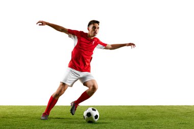 Kırmızı-beyaz üniformalı futbolcu, uzun mesafe pasına hazırlanıyor, yeşil sahada antrenman sırasında bacağını havada sallarken hareket halinde. Spor müsabakaları konsepti, final maçı. Ad