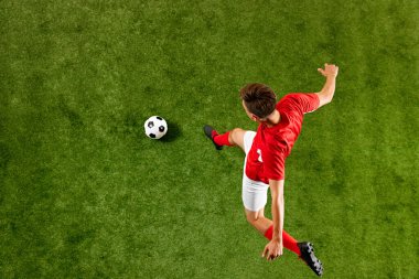 Hava görüntüsü. Kararlı futbolcu yeşil çimenli stadyumdaki antrenman sırasında topa güçlü bir atlayış sergiliyor. Şampiyonluk konsepti, spor müsabakaları, final maçı. Ad