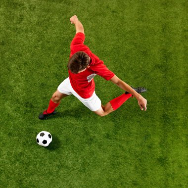 Kırmızı-beyaz kıyafetli genç futbolcu, top sürerken hassas bir şekilde antrenman yapıyor, stadyumda topu kontrol ediyor. Hava görüntüsü. Şampiyonluk konsepti, spor müsabakaları, final maçı. Ad