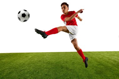 Genç atletik adam, futbol oyuncusu, kırmızı ve beyaz üniforma giymiş, yüksek tekme atıyor, yeşil sahada hassas bir şekilde topu kontrol etmeye odaklanıyor. Şampiyonluk konsepti, spor müsabakaları, final maçı