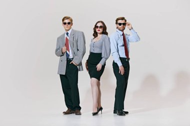 Cesur, şık ve iş için hazır. Üçlü, zamansız ofis stili ile havalı, sallanan spor ceketler, keskin etekler ve beyaz stüdyo arka planıyla bağları bir araya getirir. İş anlayışı, liderlik.