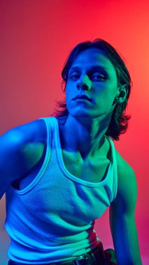 Mavi neon ışıklı portre. Uzun saçlı çekici bir adam. Stüdyonun arka planına karşı günlük kıyafetler giymiş. Doğal güzellik kavramı, moda, kozmetik ürünler, erkek sağlığı. Ad