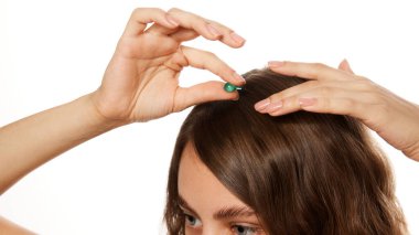 Eller kafa derisine küçük kapsül tedavisi uyguluyor, beyaz stüdyo arka planına karşı saç bakımını ve güzellik sağlığını temsil ediyor. Güzellik, moda, görünüş, özgüven kavramı. Ad