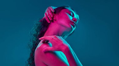 Işıl ışıl cildi vurgulayan zarif bir duruş, neon ışıkla modern, sanatsal bir güzellik anlayışı yaratıyor, cilt bakımları ve yüksek moda kampanyaları için mükemmel. Görünüm kavramı, kişisel bakım. Ad