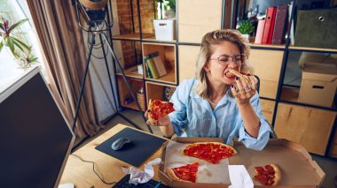 Çalışırken pizza yiyen genç bir kadın, önemli bir toplantıda. Çalışmak yerine yiyeceğe odaklanması kötü çoklu görev alışkanlıklarını vurguluyor. İş kavramı, insanlar ve günlük iş sorunları. Ad.