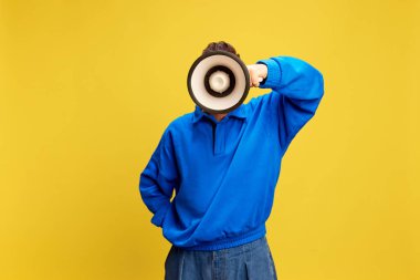 Person holds megaphone close to face and rests their hand on hip in casual pose against yellow background offers bright, approachable tone. Concept of message, journalism, advertisement. Ad clipart