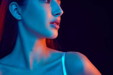 Canlı neon ışığı altında model profili, onun özgüvenli özelliklerini siyah stüdyo arka planına karşı vurgular. Görünüş ve güzellik. Kadınlık kavramı, vücut estetiği, kozmetik. Ad
