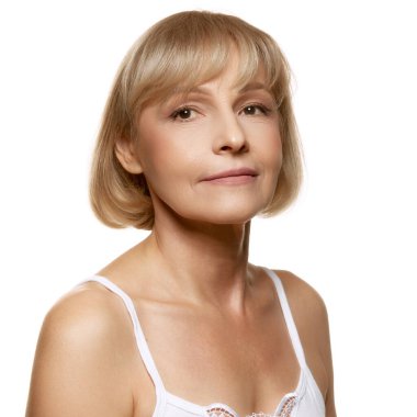 Orta yaşlı kadın portresi, derisi bakımlı, beyaz stüdyo arka planında kameraya bakıyor. Güzellik rutini. Güzellik, sağlık, kozmetoloji, yaşlanmayı önleyici ürünler. Ad