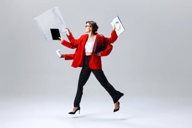 İş kadını havada zıplıyor, tablet, pano ve kahve tutuyor, modern çoklu görev ve hızlı iş hayatını temsil ediyor. Hız kavramı, çoklu görev, modern iş kadını