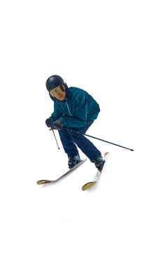 Tam hareket halinde, kayakçı bayır aşağı eğiliyor, kutuplar beyaz stüdyo arka planına karşı kontrol için açılı. Duruşundaki kararlılık spora olan bağlılığını gösteriyor. Aşırı kış sporları kavramı. Ad