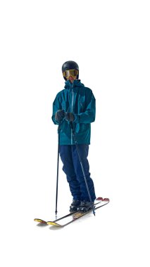 Başarılı bir koşudan sonra ayakta duran kayakçı, beyaz stüdyo arka planına karşı tam kış teçhizatıyla güven içinde poz veriyor ve macera sonrası sakinliği yakalıyor. Aşırı kış sporları, tatil kavramı