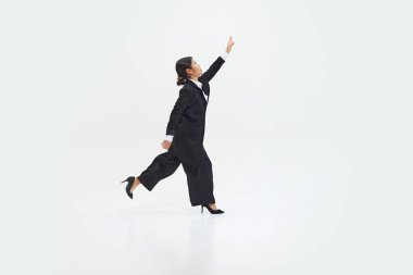 İş kadını enerjik bir şekilde koşarken, sanki beyaz stüdyo geçmişine karşı bir amaca ulaşmak istiyor gibi. DEI kavramı, iş, ortaklık, çalışma, destek ve birlik.