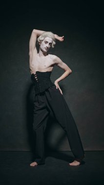 Zarif ortaçağ insanı, narin denge pozu vererek klasik portreye sanatsal bir kafa sallama ile minimalist moda sergiliyor. Füzyon kavramı modern ve klasik, sanat, müzik ve parti, bale.