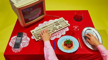 Retro masa, spagetti, bir bardak şarap ve klasik klavye ile yakın plan. Yemek ve iş malzemelerinin bir araya getirilmesiyle ayarlanmış. İş kavramı, iş hayatı dengesi. Pop sanat renkleri. Nostalji.