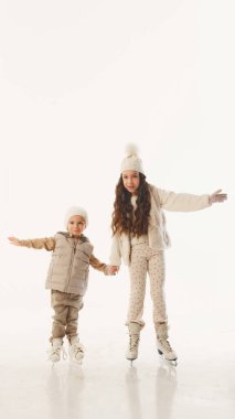 Erkek ve kız kardeşler el ele süzülerek beyaz stüdyo arka planına rağmen bayram kaykay günlerinin çoğunu geçirdiler. Kış zamanı kavramı, yeni yıl tatili, Noel tatili. Ad