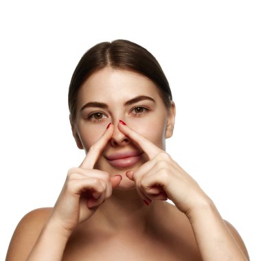 Güzellik rutini. Kadın, beyaz arka planda cilt bakımı için burun köprüsünü çimdikliyor. Güzellik, sağlık, tazelik, sağlık, güven kavramı. Ad