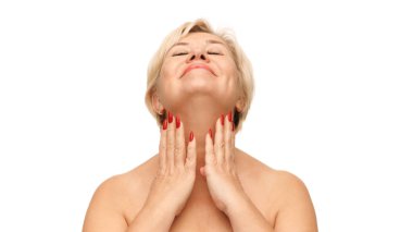 Kadın başını arkaya eğiyor, gözleri kapalı, elleri kırmızı tırnaklarıyla yavaşça boynuna dokunuyor beyaz stüdyo arka planına. Doğal güzellik kavramı, spa tedavisi, kozmetoloji.