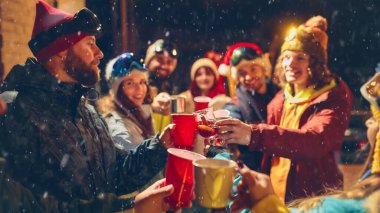 Kayak temalı bir grup yakın arkadaş açık havada içki ve kahkaha paylaşıyor. Etrafı kar yağışı ve tatil süslemeleriyle çevrili. Tatil kavramı, Noel partisi. Ad