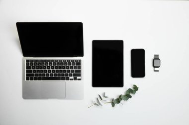 Laptop, tablet, akıllı telefon ve akıllı saat sehpası, okaliptüs yeşiliyle dengelenmiş, modern ve düzenli ayarlar. İş kavramı, pazarlama, estetik, teşvik.