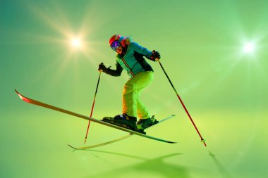 Freestyle skier mid-air, executing dynamic jump with bent knees and balanced posture, dressed vibrant gear against glowing studio background. Concept of extreme sport, Christmas holidays. Ad clipart