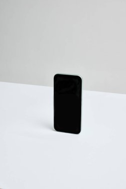 Akıllı telefon nötr masada dikey pozisyonda. Kaplamalar, markalaşma veya uygulama tasarımları için yeterli negatif alan. İş kavramı, pazarlama, estetik, teşvik.
