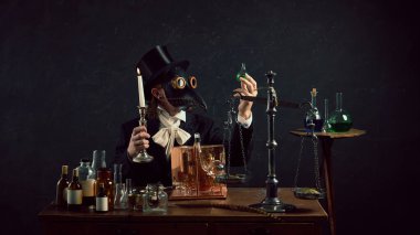 Eskimiş tıbbi aletlerle ve gizemli arka planda cam örtülerle çevrili eski tip laboratuardaki düşünceli veba doktoru. Dönem, tıp, bilim ve ilaç karşılaştırması kavramları. Ad