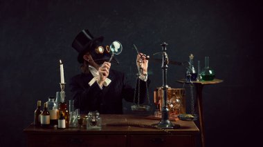 Simyacıdan esinlenilmiş veba doktoru, eskimiş terazileri esrarengiz karanlık geçmişle karşılaştırmak için klasik laboratuvarda dengeliyor. Dönem, tıp ve ilaç karşılaştırmaları kavramları. Ad