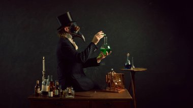 Plague doctor mixing his elements, experimenting and researching in vintage laboratory against dark mystery background. Concept of comparisons of eras, medicine, science, pharmaceutical. Ad clipart