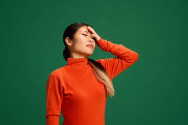 Genç Asyalı kadın yeşil stüdyo geçmişiyle el ele tutuşurken kendini kötü hissediyor. Bayılmadan önce modellik yap. Sağlıklı yaşam tarzı kavramı, kış, hastalık, iltihap. Ad