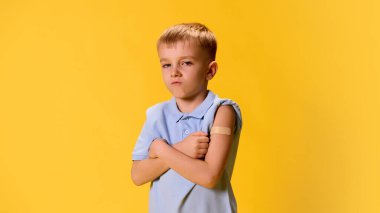 Mutsuz küçük bir çocuk, çocuk sarı arka planda göğüsteki aşılarla el ele vermiş. Sağlık, koruma, dokunulmazlık, önleme kavramı. ad
