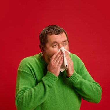 Burnu dokularla silen, ifadesini değiştiren, hasta ve yorgun, soğuk belirtileri gösteren, hapşıran ve virüs etkisi yapan bir adam. Sağlık, ilaç, enfeksiyon ve tedavi kavramı. Ad.