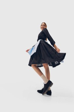 Siyah kıyafetli bayan garson, beyaz stüdyo geçmişine karşı dinamik görünürken geri çekiliyor. Geniş açı. Başarı kavramı, profesyonel gelişme, hareket. Ad